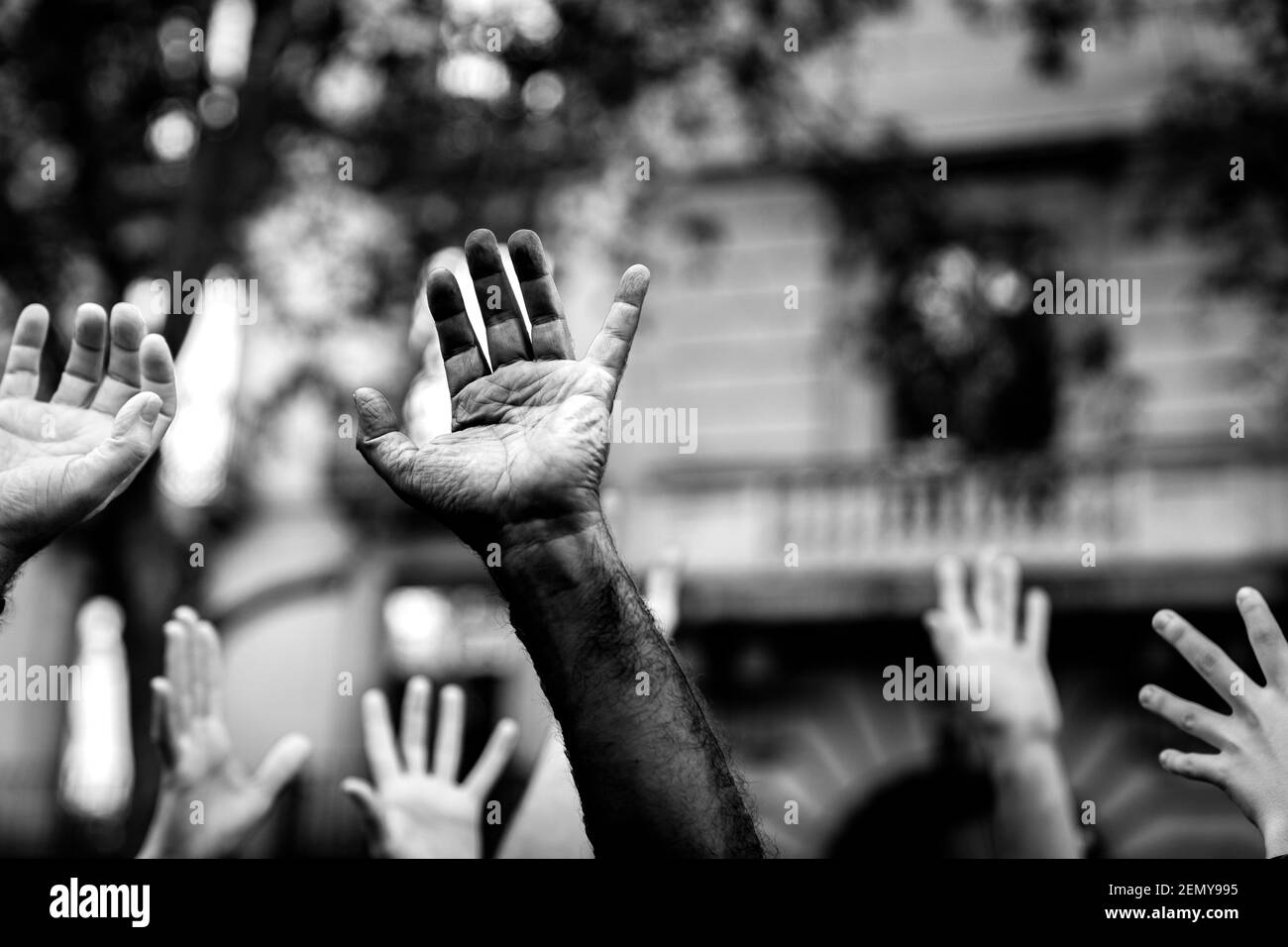 Des mains multiculturelles soulevées dans l'air demandant la liberté dans une manifestation dans la rue en noir et blanc. Ouvrir la paume d'une main noire et les mains blanches. S Banque D'Images