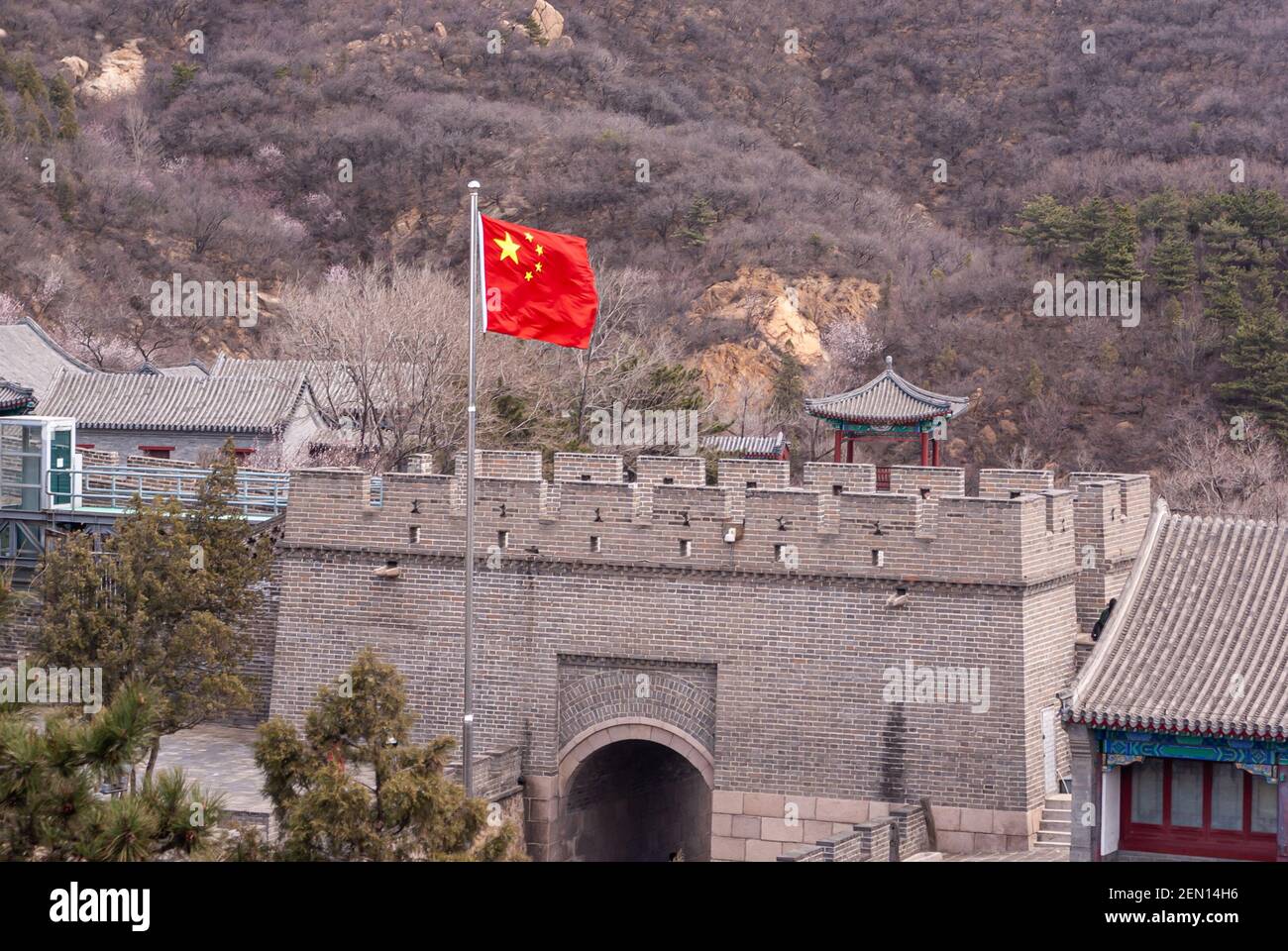 Pékin, Chine - 28 avril 2010 : Grand mur de Chine. Gros plan du drapeau rouge chinois sur le dessus du bâtiment de la porte. Collines brunes en toile de fond. Un peu de feuillage vert Banque D'Images