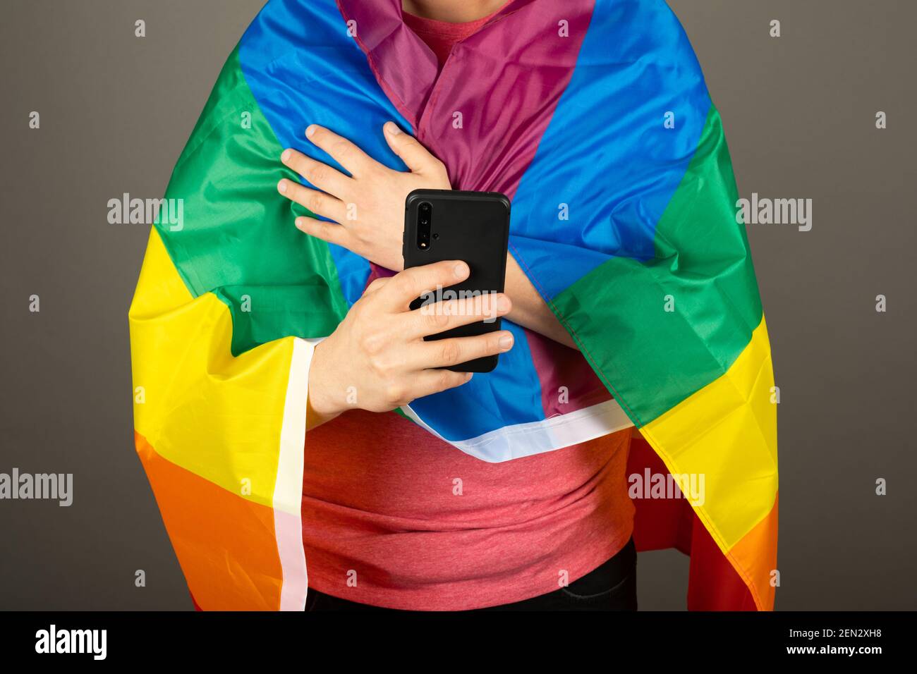 Homme gay portant un t-shirt rose et un drapeau arc-en-ciel Banque D'Images