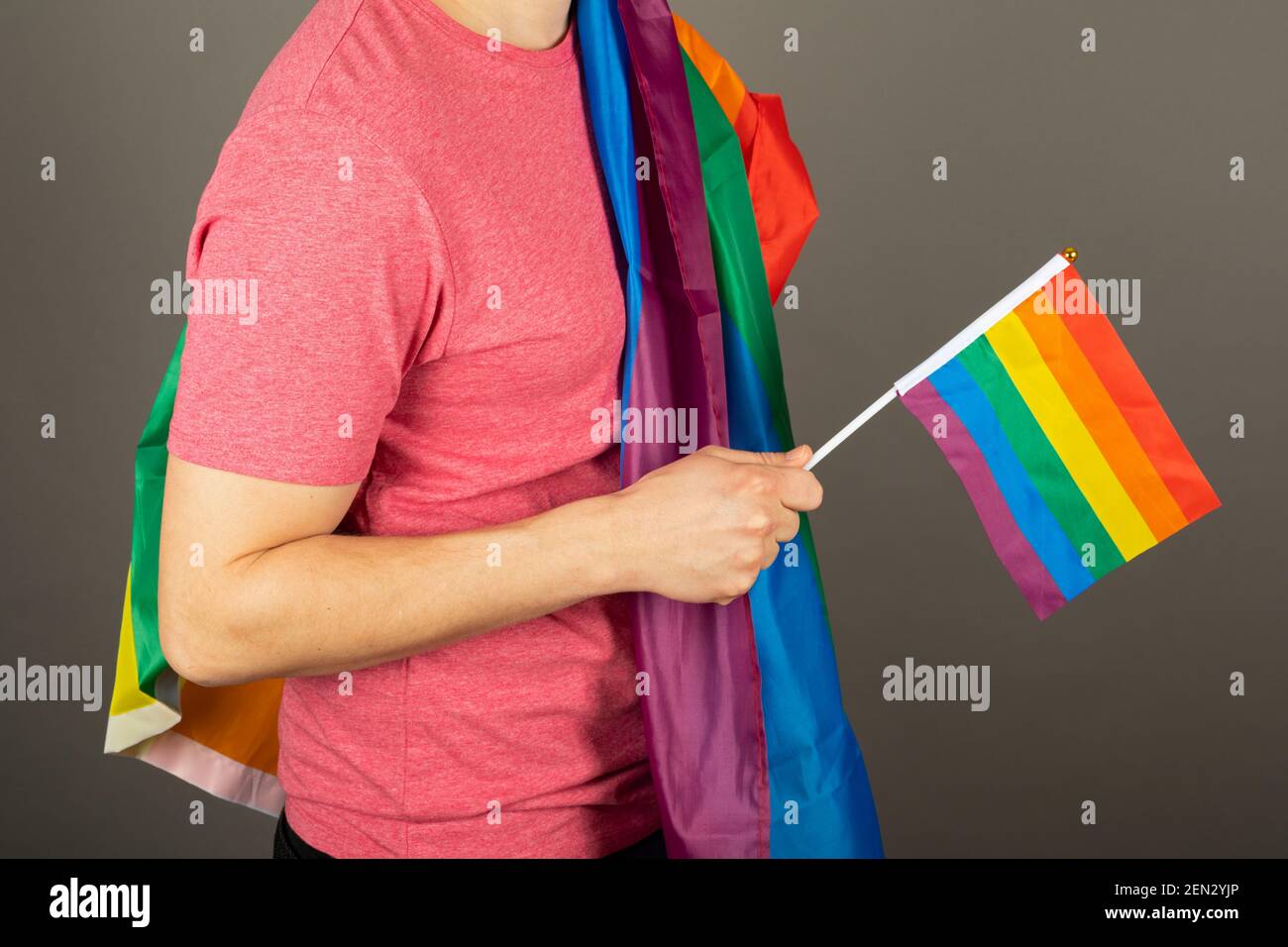 Homme gay portant un t-shirt rose et un drapeau arc-en-ciel Banque D'Images