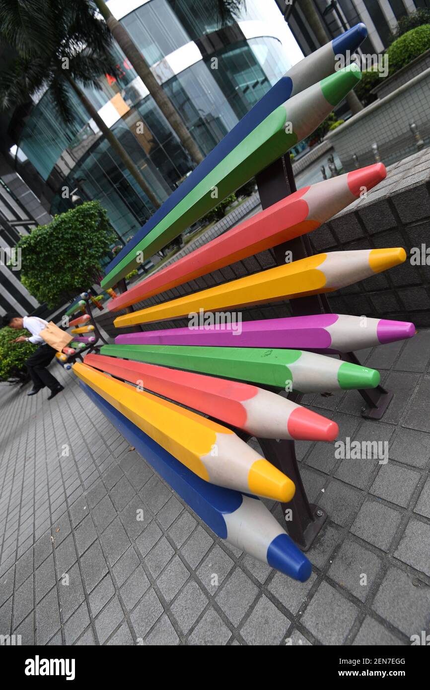 Un homme chinois est assis sur un banc de crayons de couleur à côté  d'autres sur une place parmi les immeubles de bureaux dans la ville de  Guangzhou, dans la province de