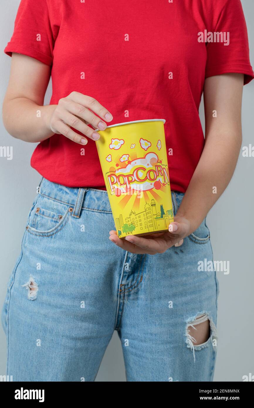 Jeune fille en chemise rouge tenant une boîte de popcorns Banque D'Images