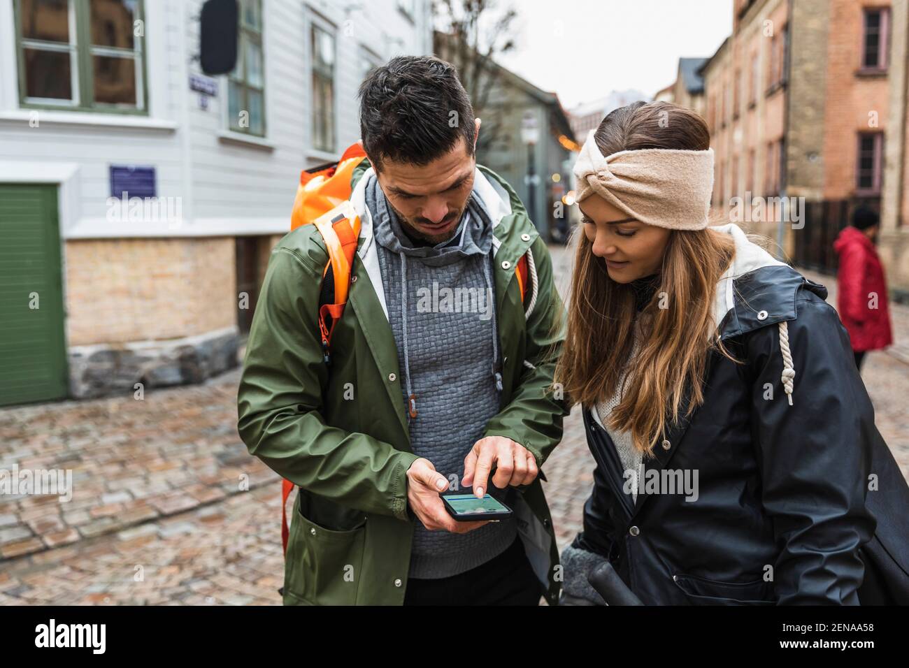 Couple hétérosexuel naviguant sur la carte d'un téléphone intelligent en ville Banque D'Images