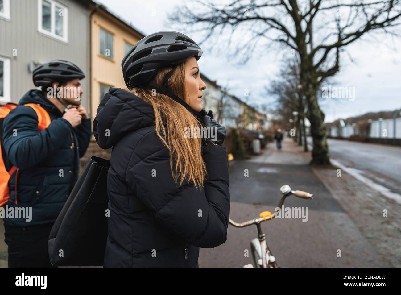 Couple hétérosexuel portant un casque de cyclisme sur le trottoir de la ville Banque D'Images