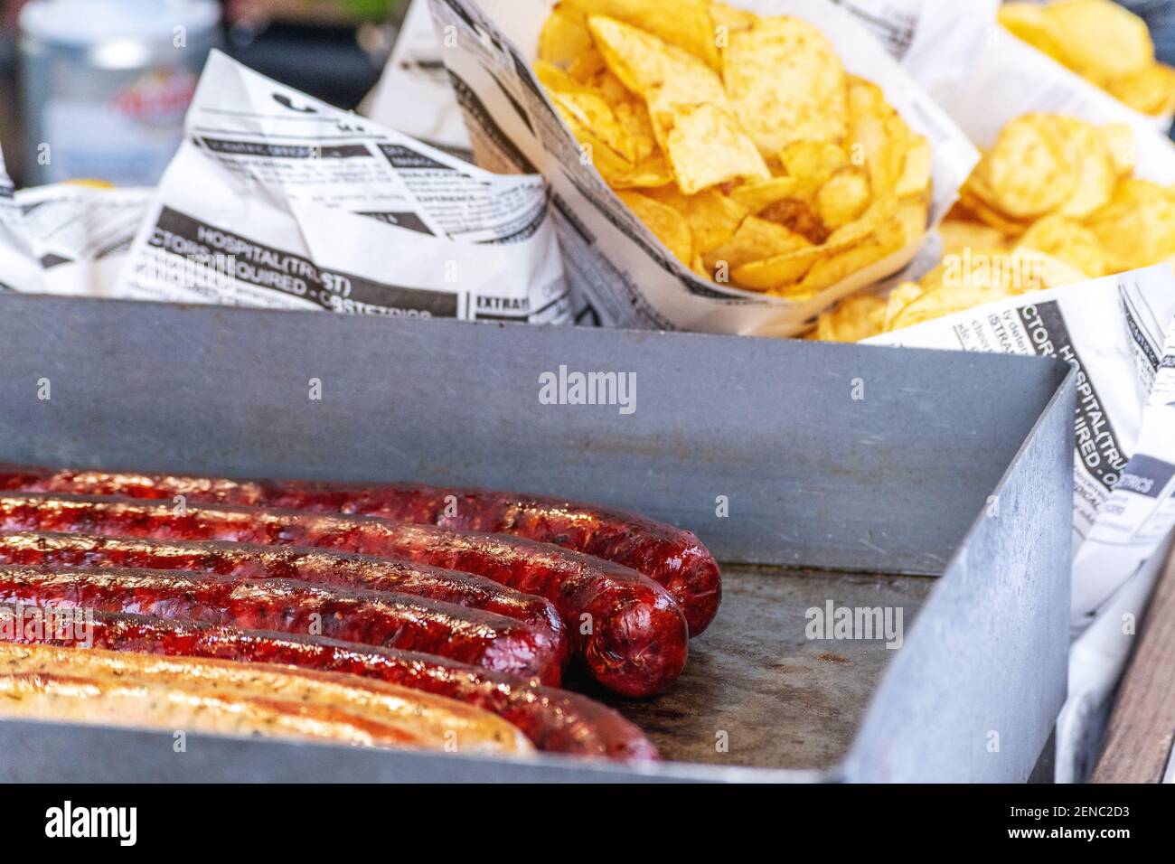 Saucisses frites et quartiers de pommes de terre frits dans un sac en papier. Concept de cuisine de rue. Banque D'Images