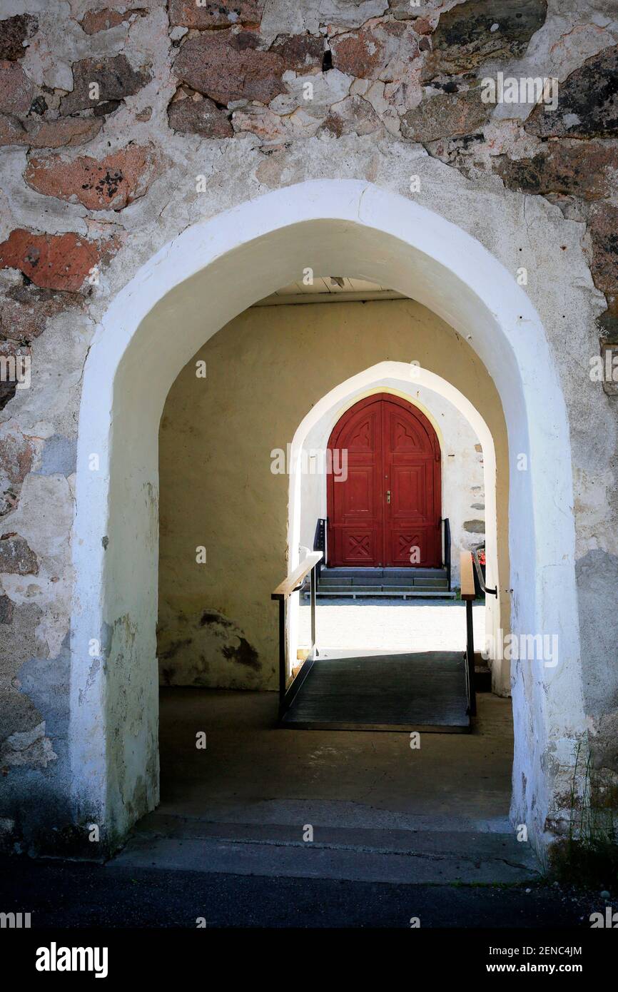 Porte d'une église médiévale en pierre avec porte principale en bois ensoleillée sur le fond. Banque D'Images