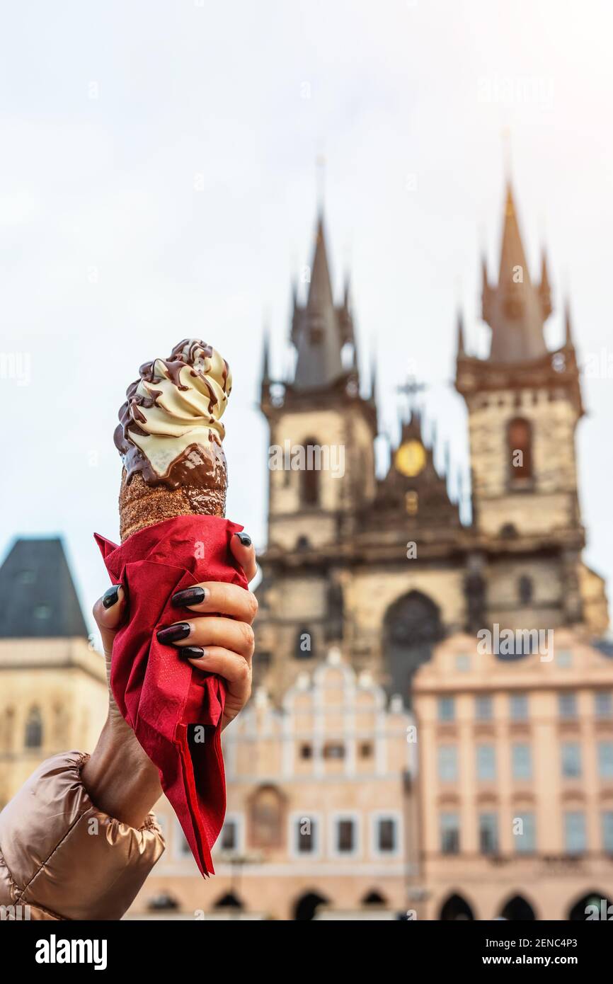 La main féminine tient le cookie tchèque traditionnel trdelnik sur le fond de la vieille ville de Prague. Banque D'Images