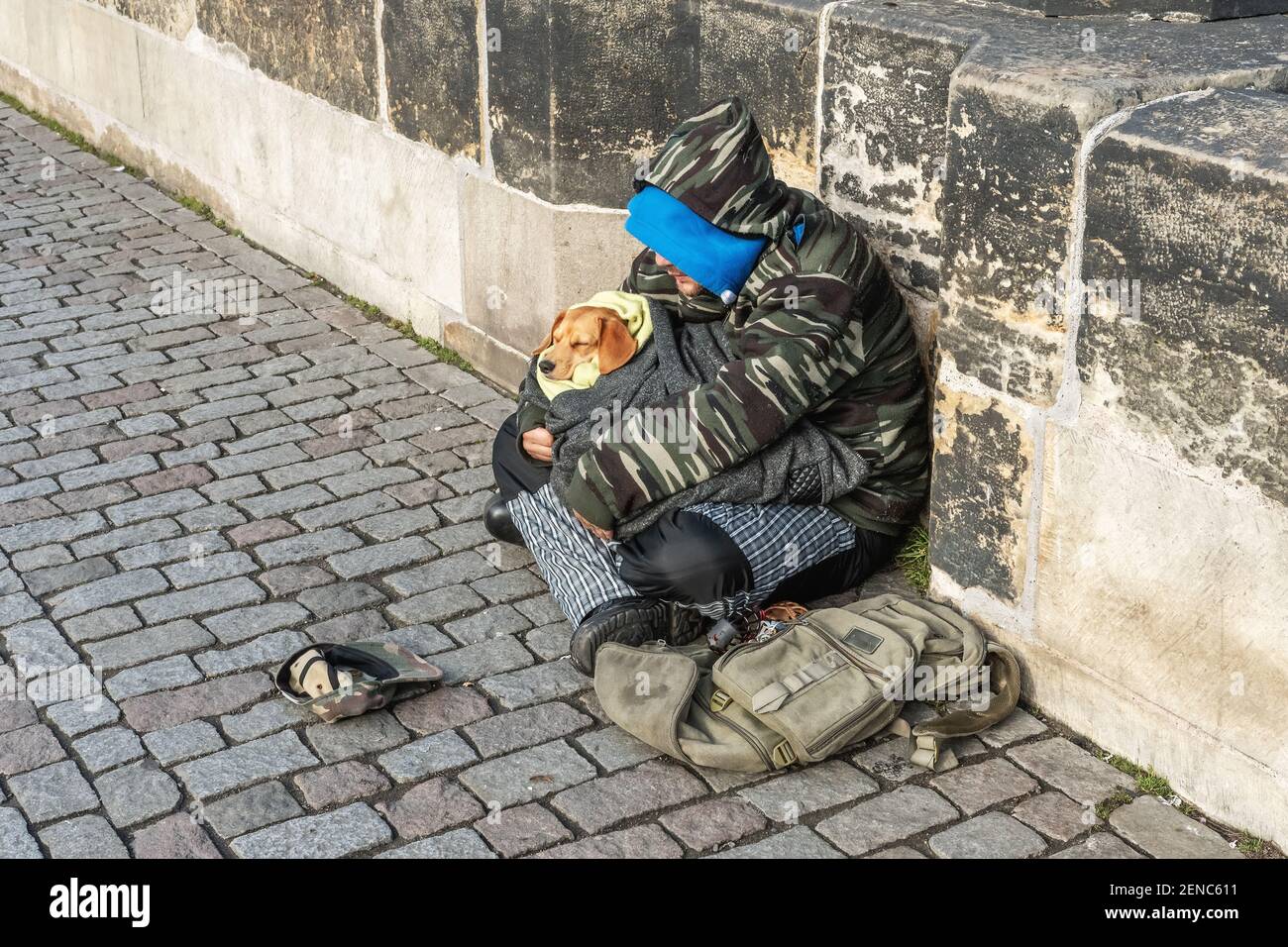Prague, République Tchèque -20 janvier 2020: Homme sans âme avec un chien assis sur le pont Charles implorant de l'aide et de l'argent. Les problèmes des grands citi modernes Banque D'Images