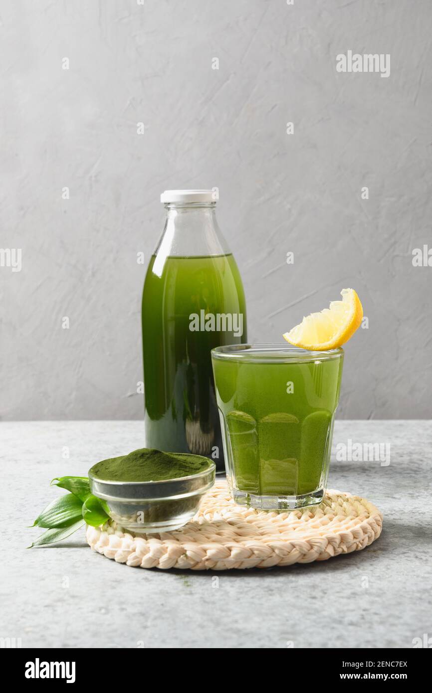 Chlorella Detox boisson avec citron dans le verre et bouteille pour la journée sur fond gris. Gros plan. Format vertical. Banque D'Images
