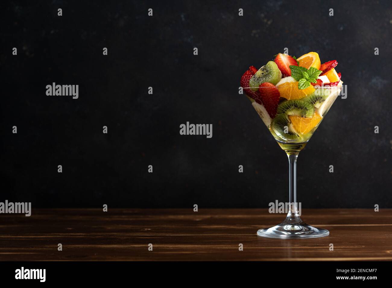 Cocktail de fruits en verre martini sur table en bois. Concept végétalien alimentaire. Banque D'Images