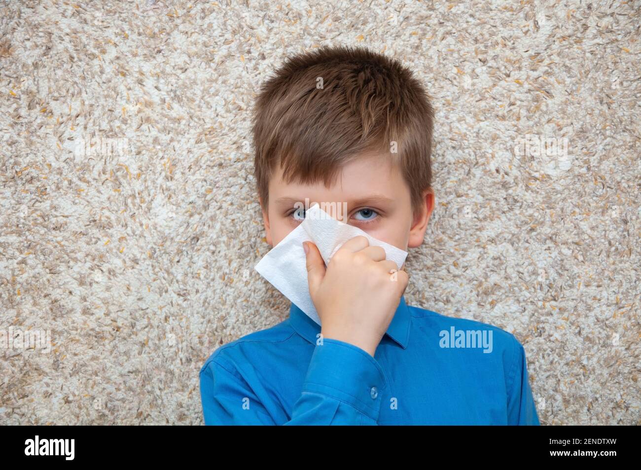 Garçon avec un virus froid essuie son nez d'un écoulement nasal Banque D'Images