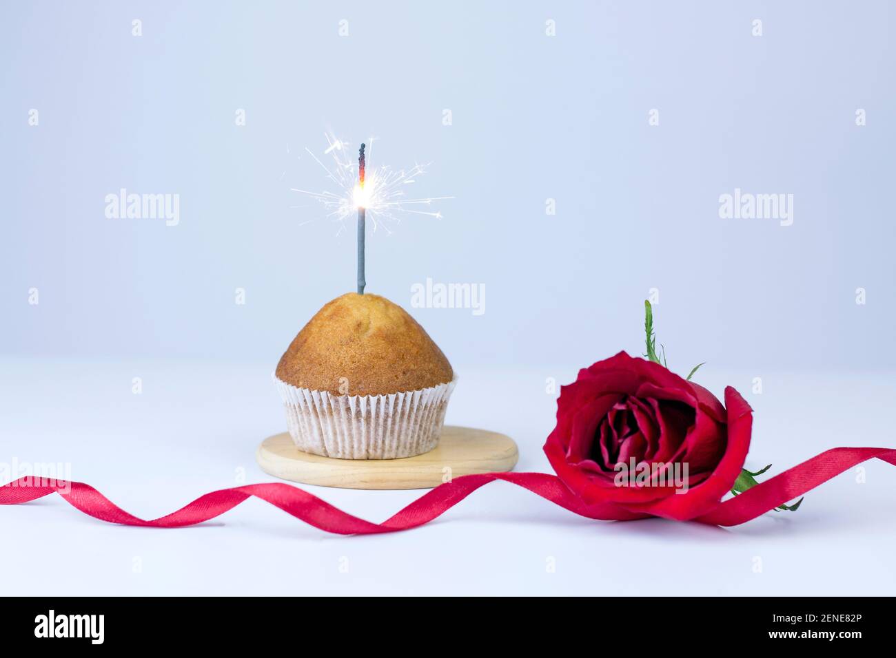 Muffin fait maison avec ruban rouge étincelant et rose sur fond blanc. Carte-cadeau des fêtes et de la Saint Valentin avec espace de copie. Banque D'Images