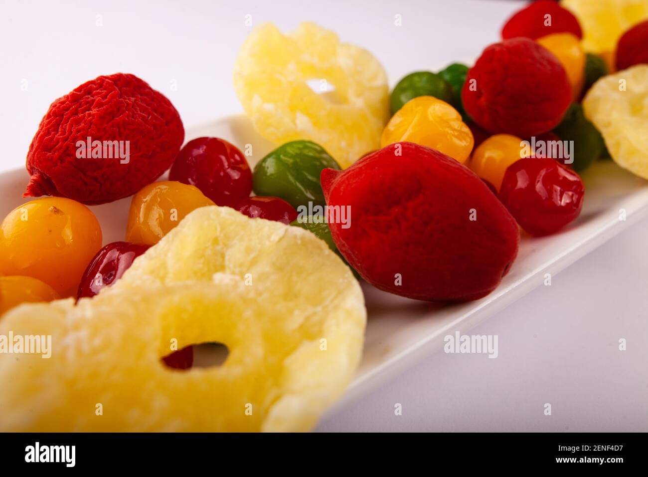 Une pile de fruits confits multicolores sur une assiette et un fond blancs. Banque D'Images