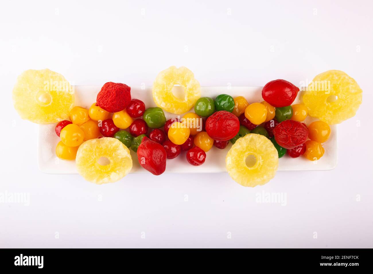 Une pile de fruits confits multicolores sur une assiette et un fond blancs. Banque D'Images