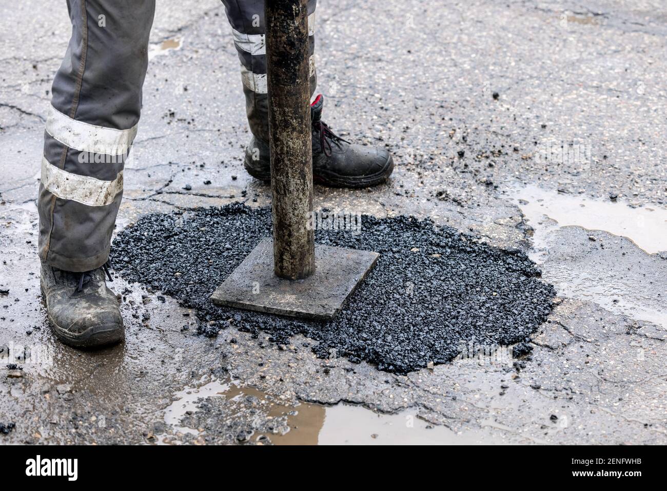 ouvrier poussant l'asphalte de bitume dans le trou. réparation et entretien des routes Banque D'Images