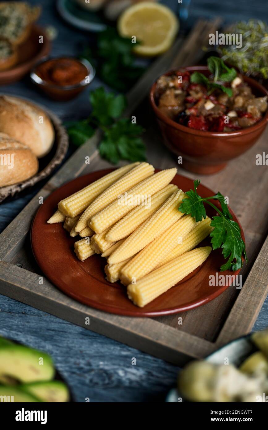 gros plan d'une assiette avec un peu de maïs sucré cuit sur une table, à côté d'un bol avec un peu d'escalivada, un plat d'accompagnement fait avec différents légumes rôtis Banque D'Images