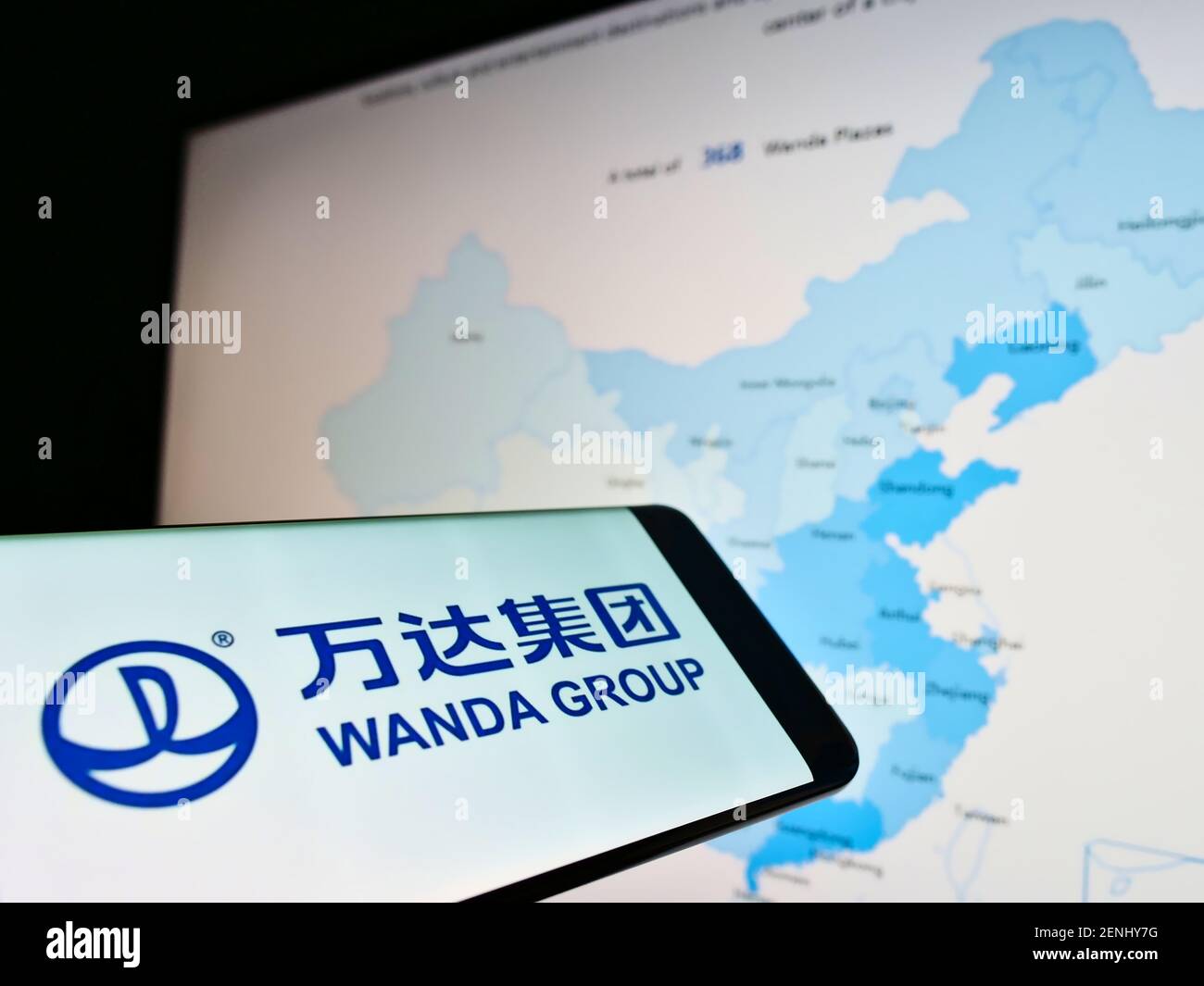 Smartphone avec le logo de la société du conglomérat chinois Wanda Group à l'écran devant le site Web avec carte. Effectuez la mise au point au centre-droit de l'écran du téléphone. Banque D'Images