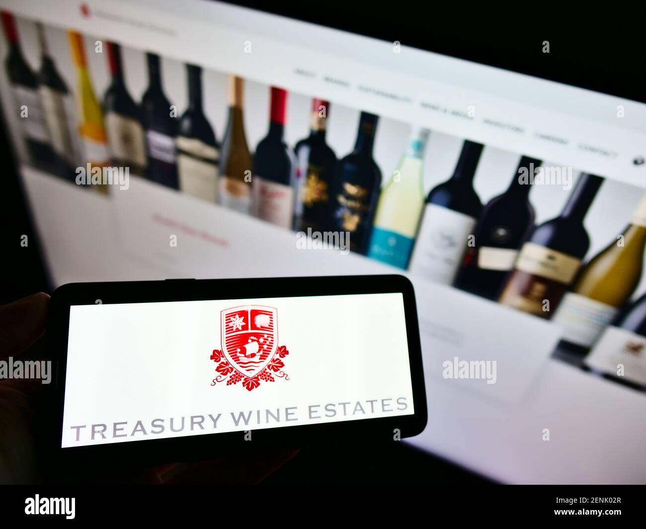 Personne tenant un téléphone portable avec le logo d'entreprise de la société australienne de vinification Treasury Wine Estates à l'écran avec le site Web. Mise au point sur l'affichage du téléphone. Banque D'Images