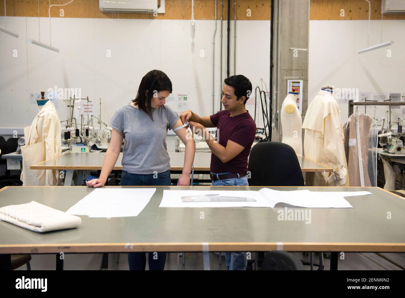 Étudiants en mode, homme mesurant le bras de la femme Banque D'Images