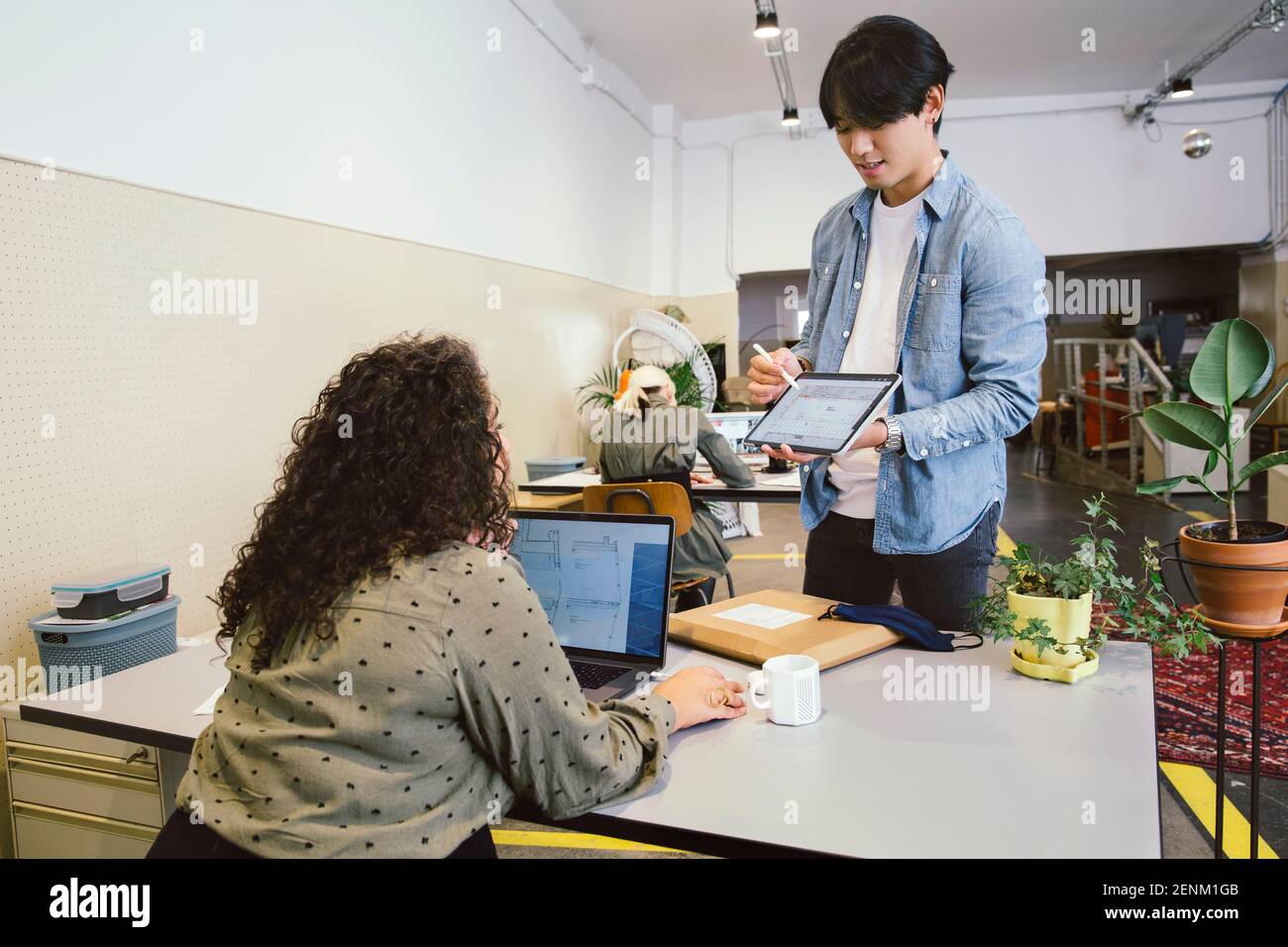 Homme montrant une tablette numérique à un collègue au bureau Banque D'Images
