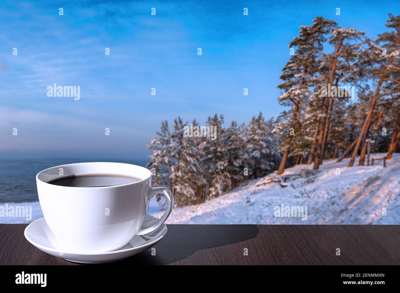 Tasse de café sur la table avec vue sur la plage enneigée, la mer Baltique et couverte de sapins et de pins sur la colline. Banque D'Images