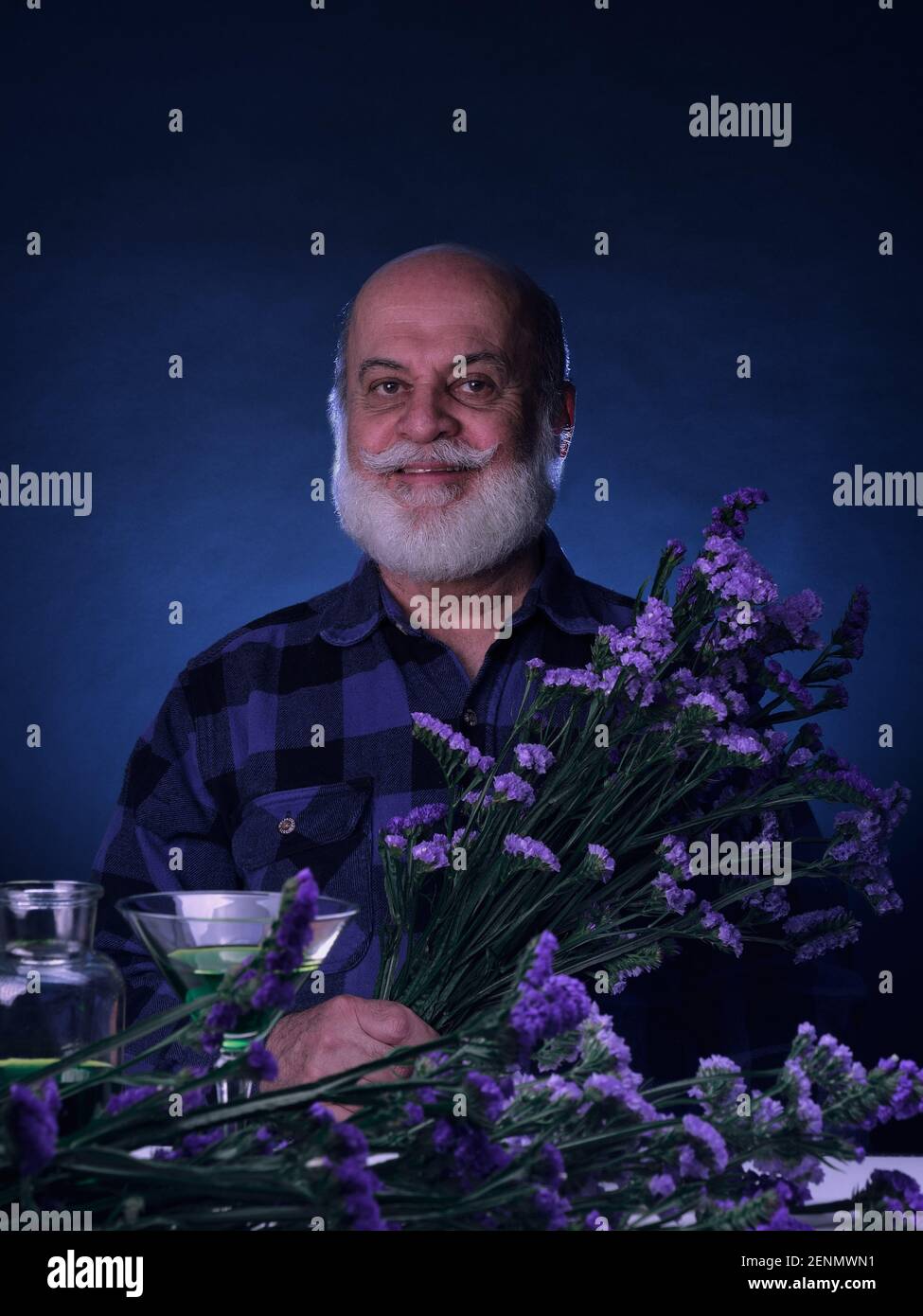 Portrait d'un homme âgé dans des tons bleus tenant un bouquet de fleurs bleues et violettes Banque D'Images