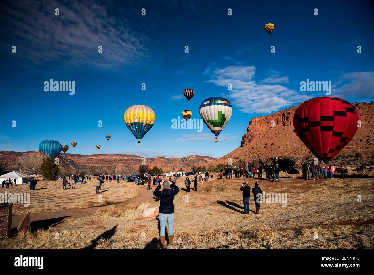 Kanab, Utah, États-Unis, 19 février 2021 - des spectateurs se rassemblent pour observer 30-40 ballons d'air chaud s'élever au-dessus des falaises rouges et du ciel bleu de Kanab, Utah, États-Unis. Banque D'Images