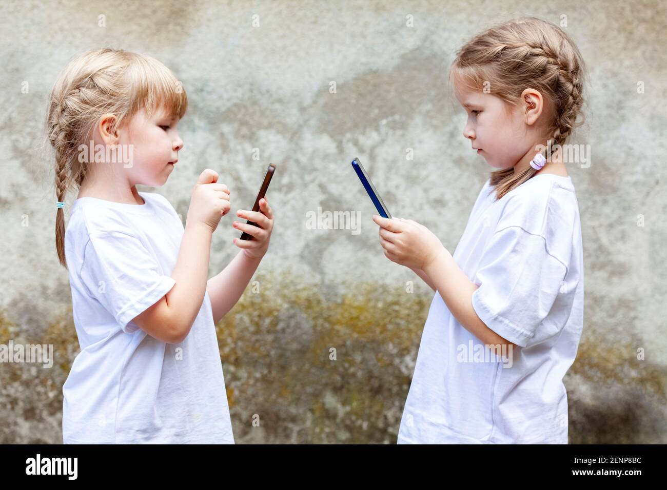 Deux petites filles, sœurs ou amis utilisant leur smartphone, les enfants envoyant des SMS sur leur téléphone mobile face à face. Enfants et technologie moderne, un Banque D'Images