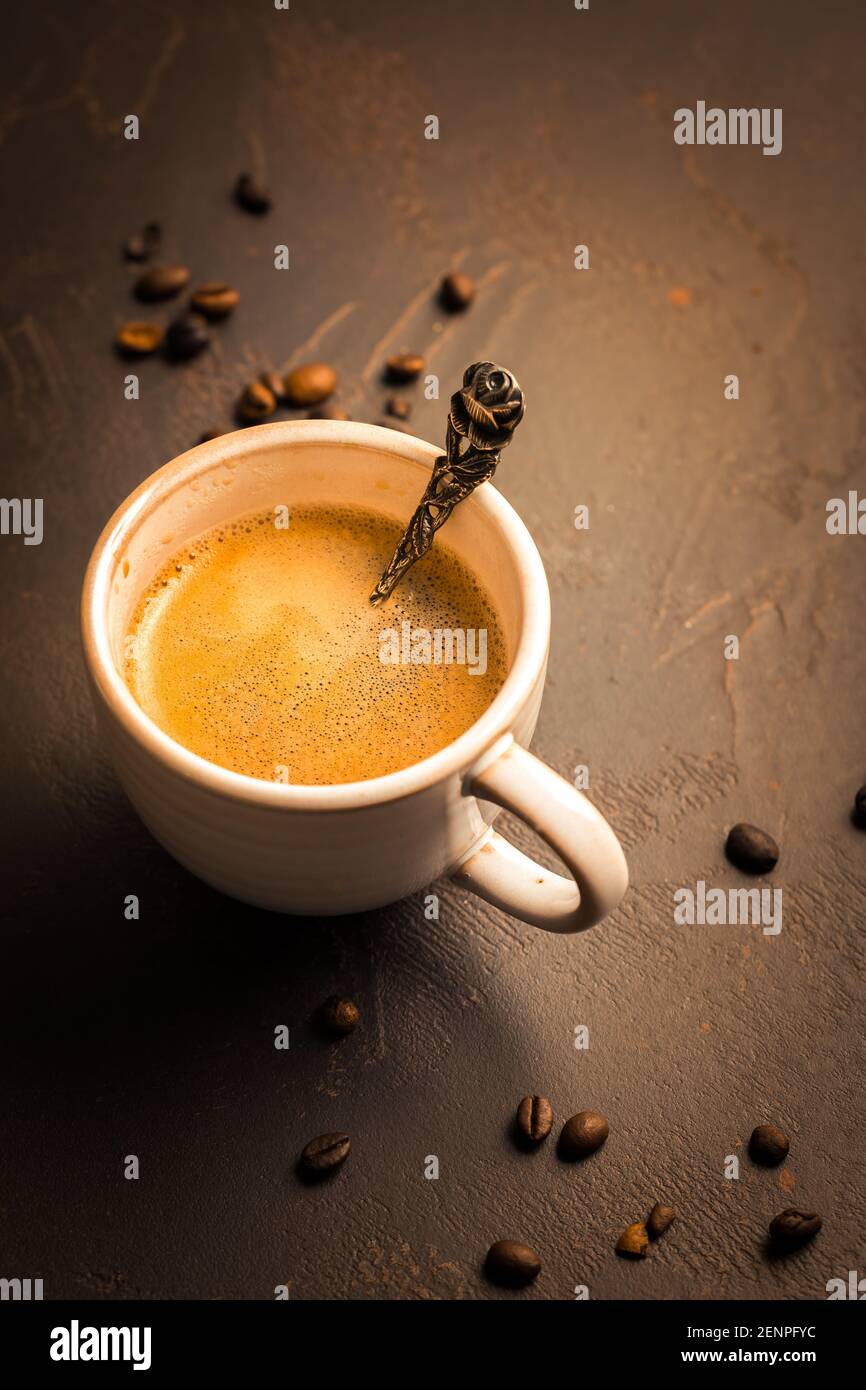 Tasse de café avec grains de café sur fond marron. Banque D'Images