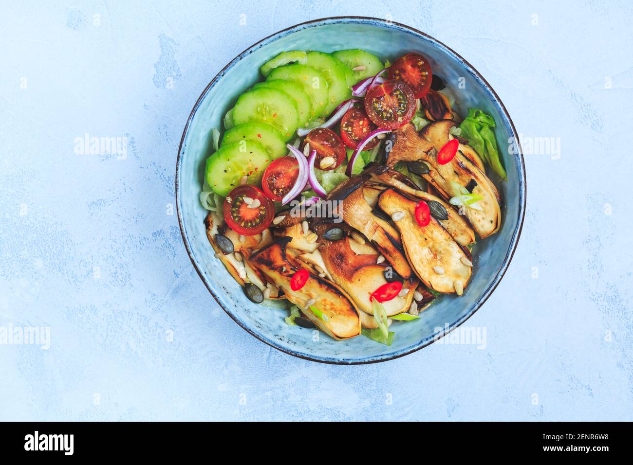 Bol à salade avec rôtissoire, champignons d'huîtres, tomate, concombre et oignon rouge. Repas sain de légumes. Banque D'Images