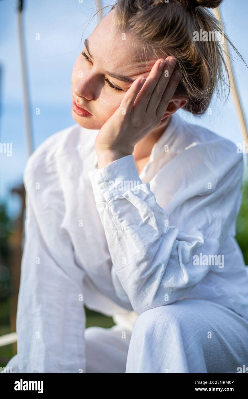 Femme européenne aux cheveux blonds avec la main près du visage portrait à l'extérieur Banque D'Images