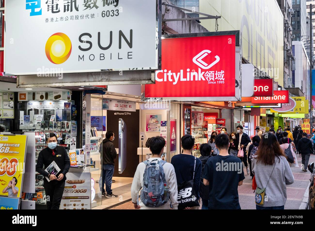 Des piétons marchent devant plusieurs sociétés de télécommunications, Sun Mobile, Citylink, magasins de Vodaphone à Hong Kong. Banque D'Images