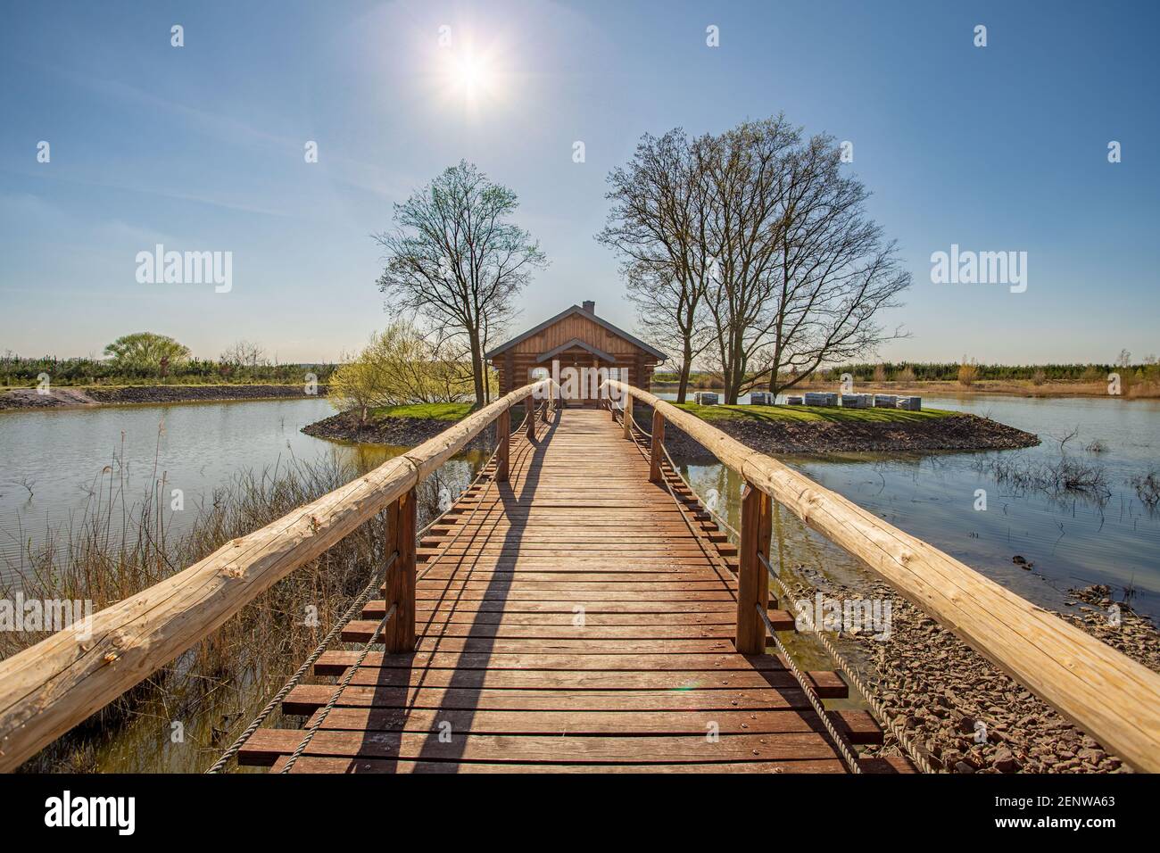 Juin 2020, Kosice, République Tchèque - au milieu du lac il y a une maison dans un petit bosquet, un pont en bois avec des rampes lui mène. L'eau Banque D'Images