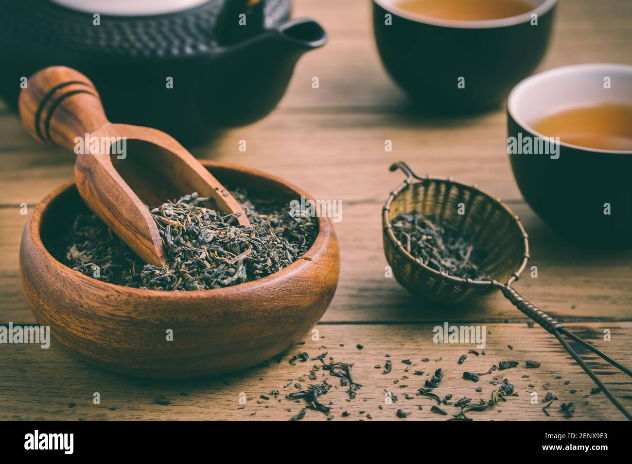 Thé noir avec feuilles de thé séchées et infuseron fond en bois Banque D'Images