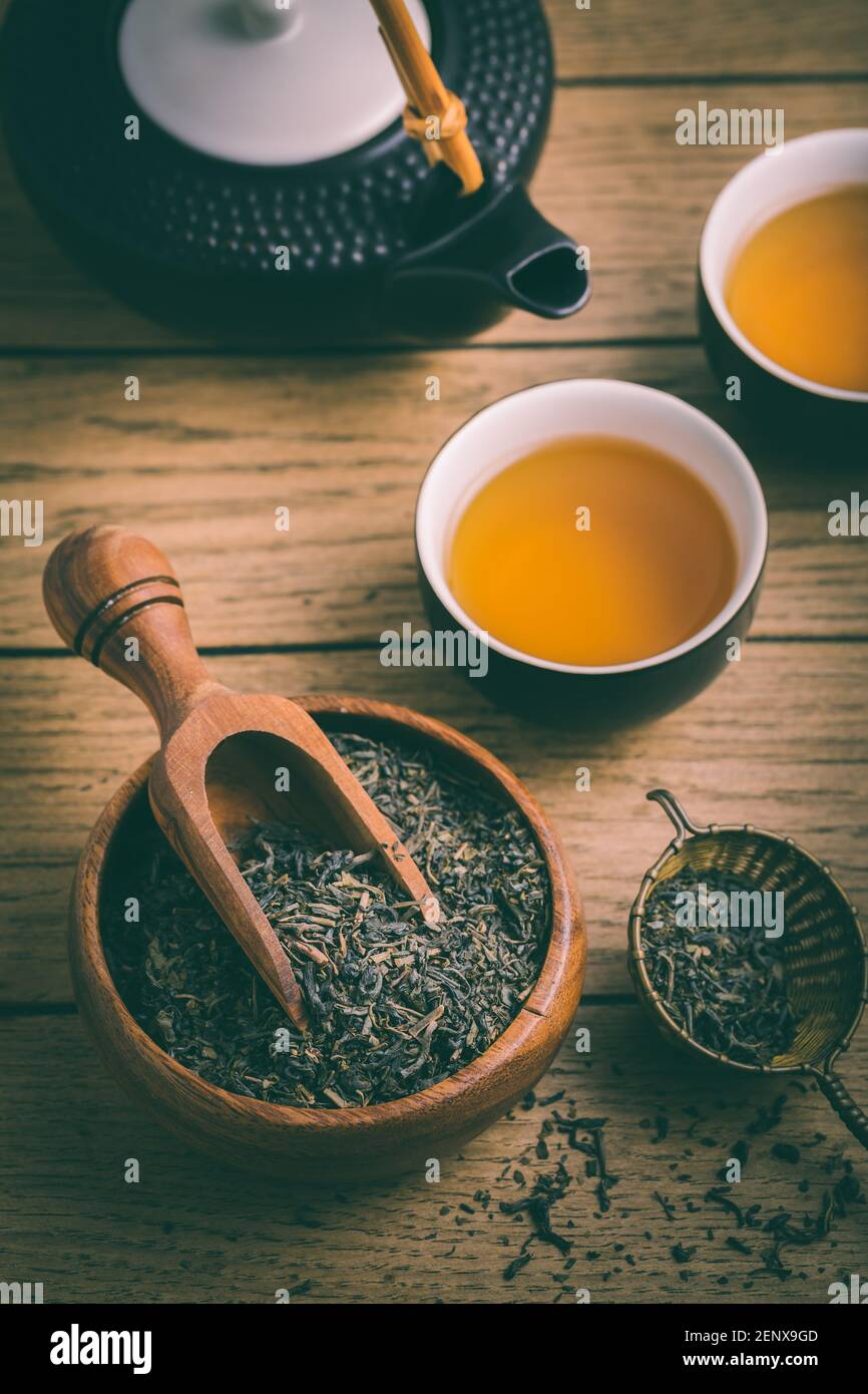 Thé noir avec feuilles de thé séchées et infuseron fond en bois Banque D'Images