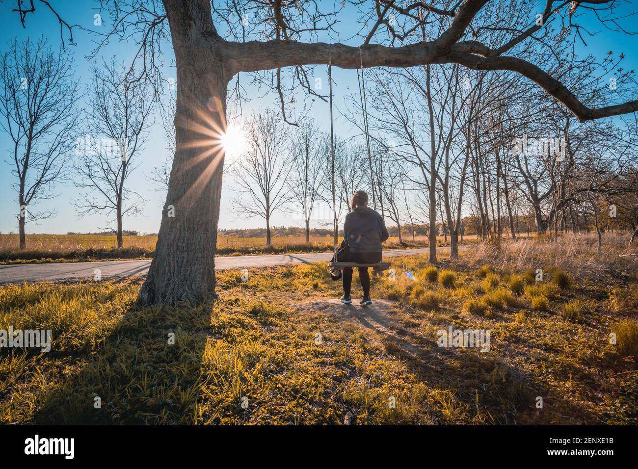 Bonne jeune femme sur un balancement avec fond de coucher de soleil Banque D'Images