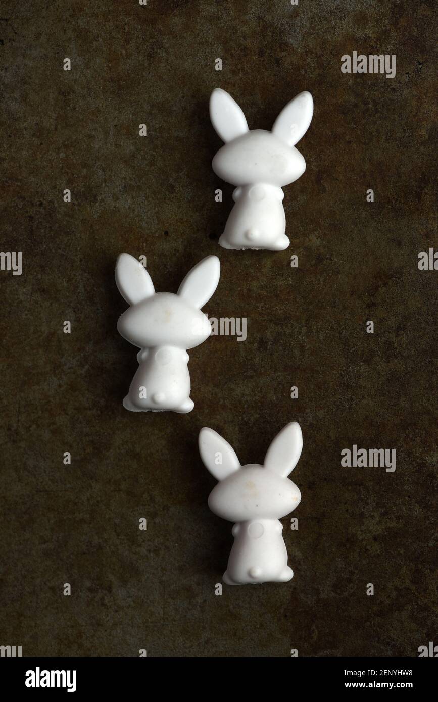 Vue en hauteur encore la vie de trois figurines de lapin jouet sur un fond métallique terni Banque D'Images