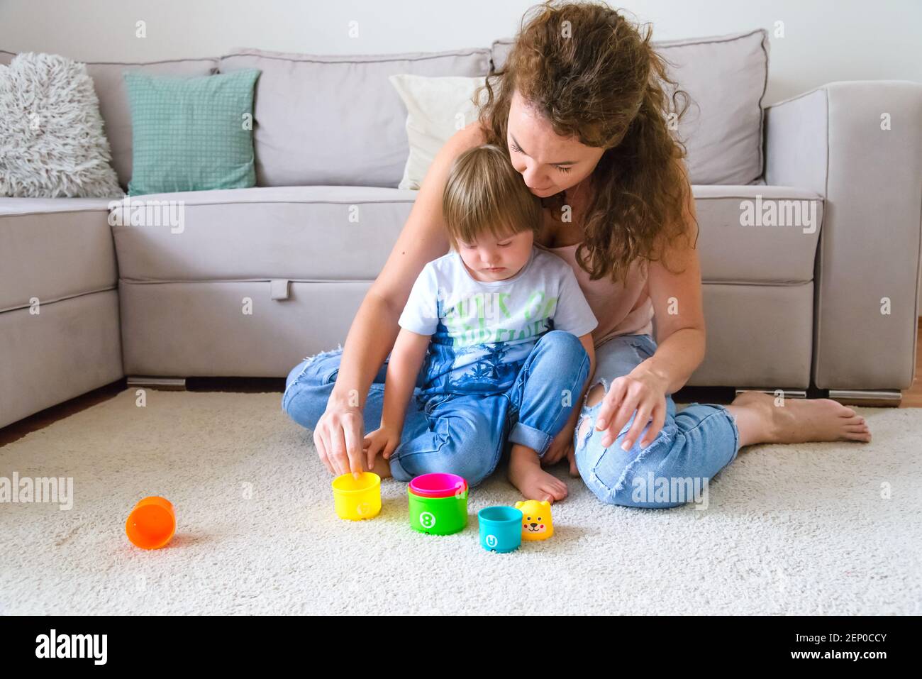 Mère célibataire jouant avec un enfant handicapé avec le syndrome de Down dans leur salon à leur appartement Banque D'Images