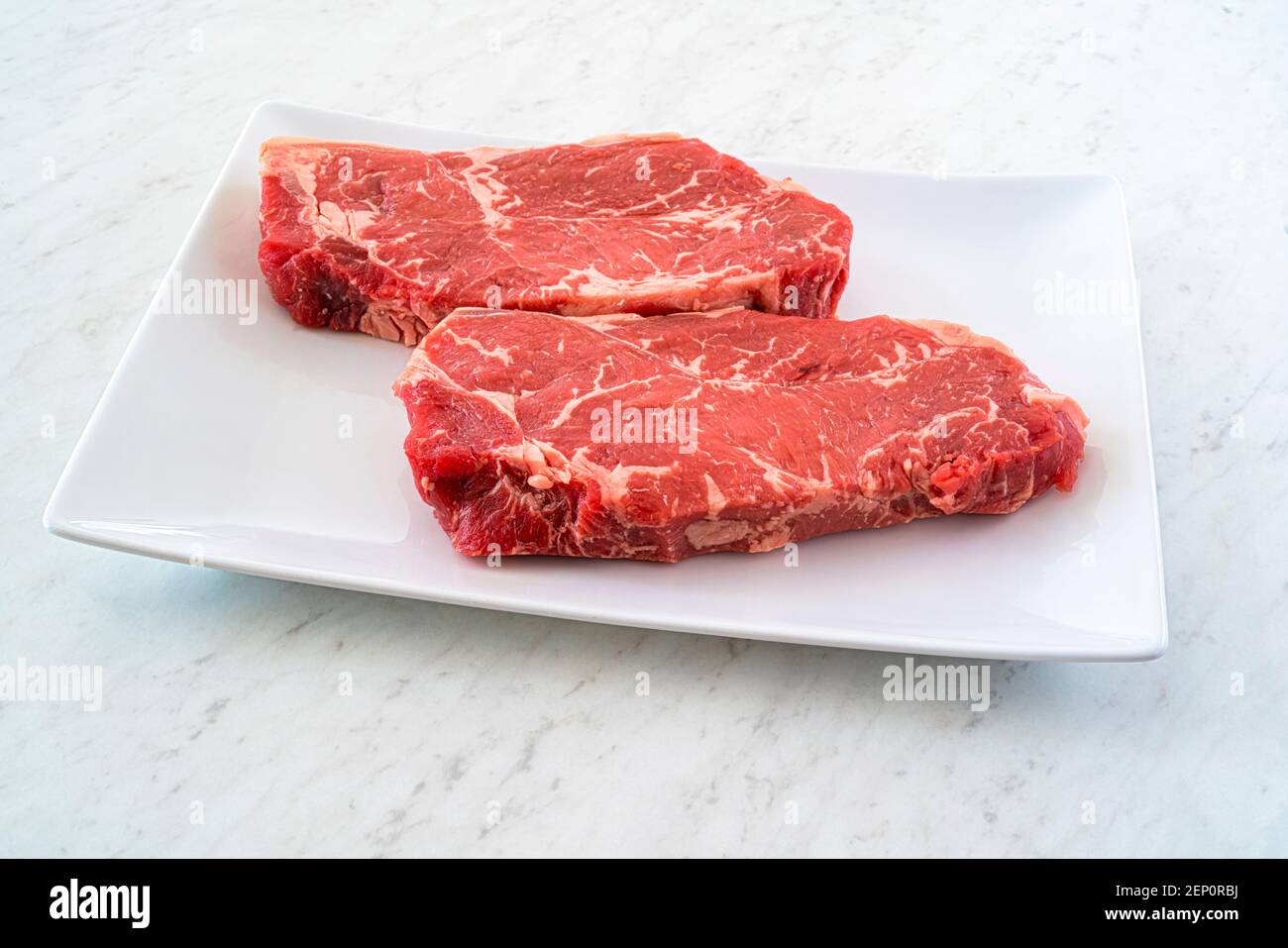 Steak de barbule de marbre sur une assiette blanche sur un comptoir en marbre. Banque D'Images