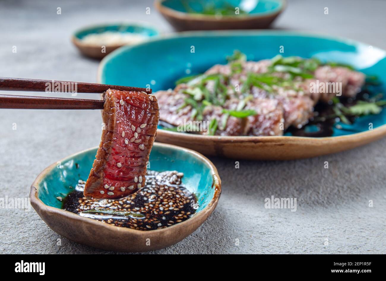 Tatataki de bœuf avec sauce et sésame sur une assiette bleue. Cuisine japonaise Banque D'Images