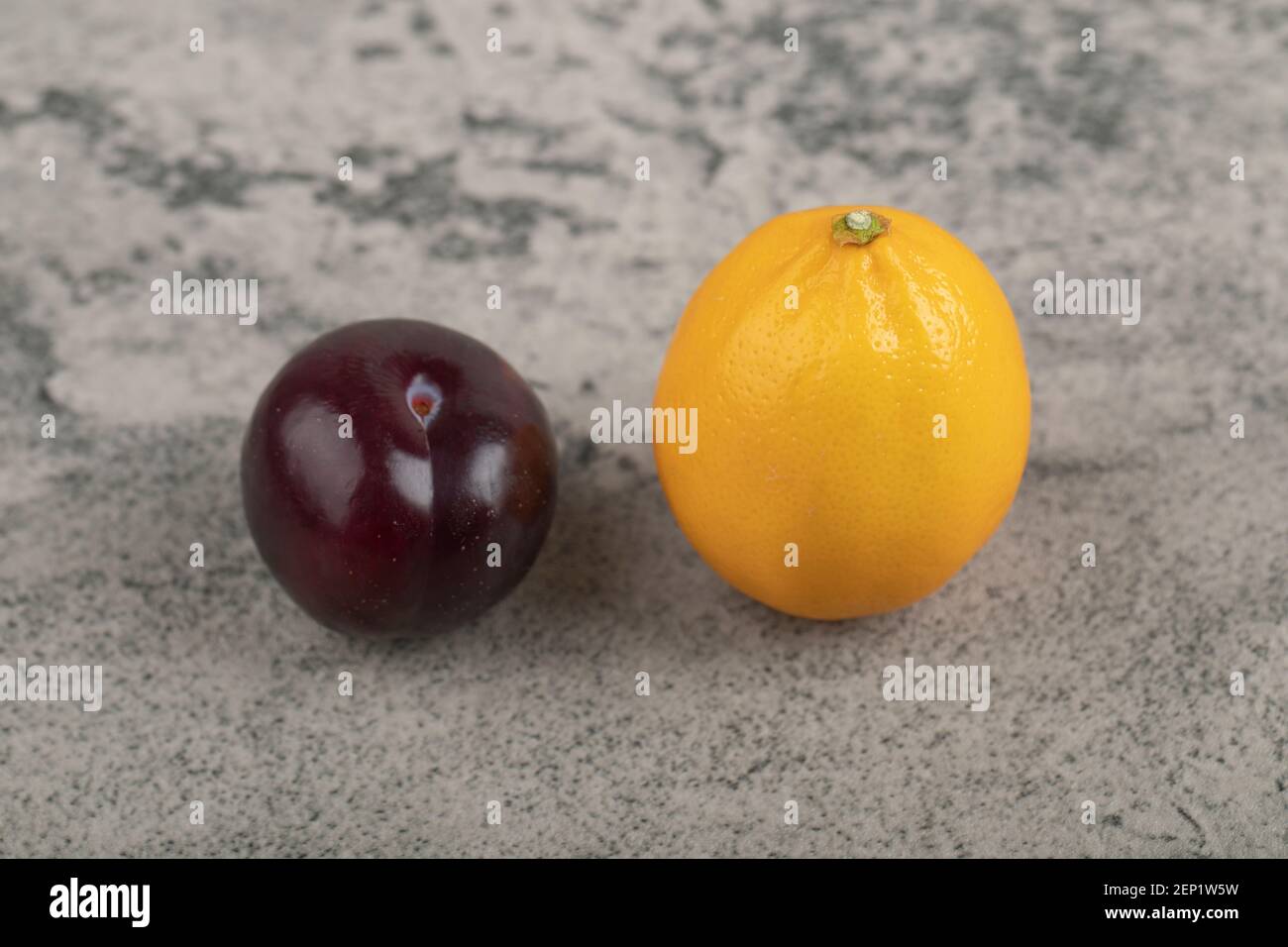 Une prune pourpre entière avec un citron entier sur la pierre arrière-plan Banque D'Images