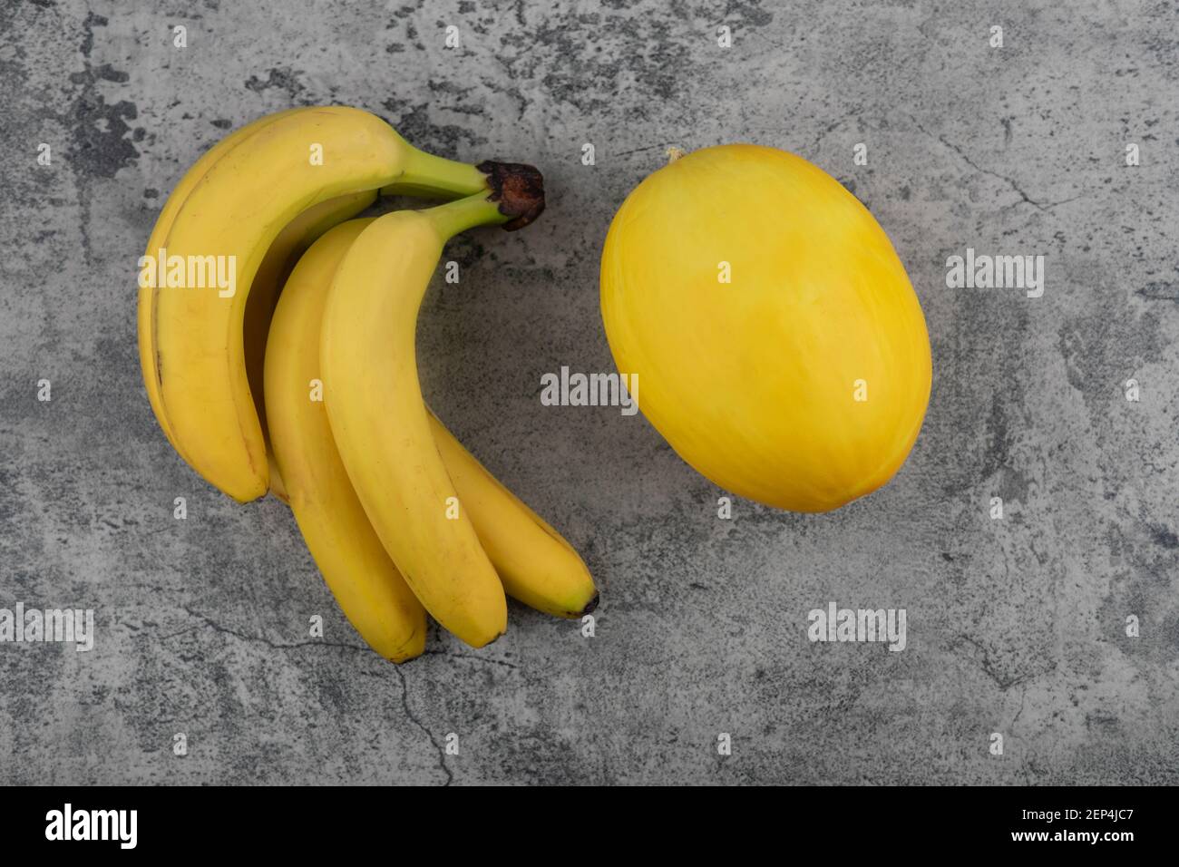 Grappe de bananes fraîches avec citrouille saine jaune sur fond de pierre Banque D'Images