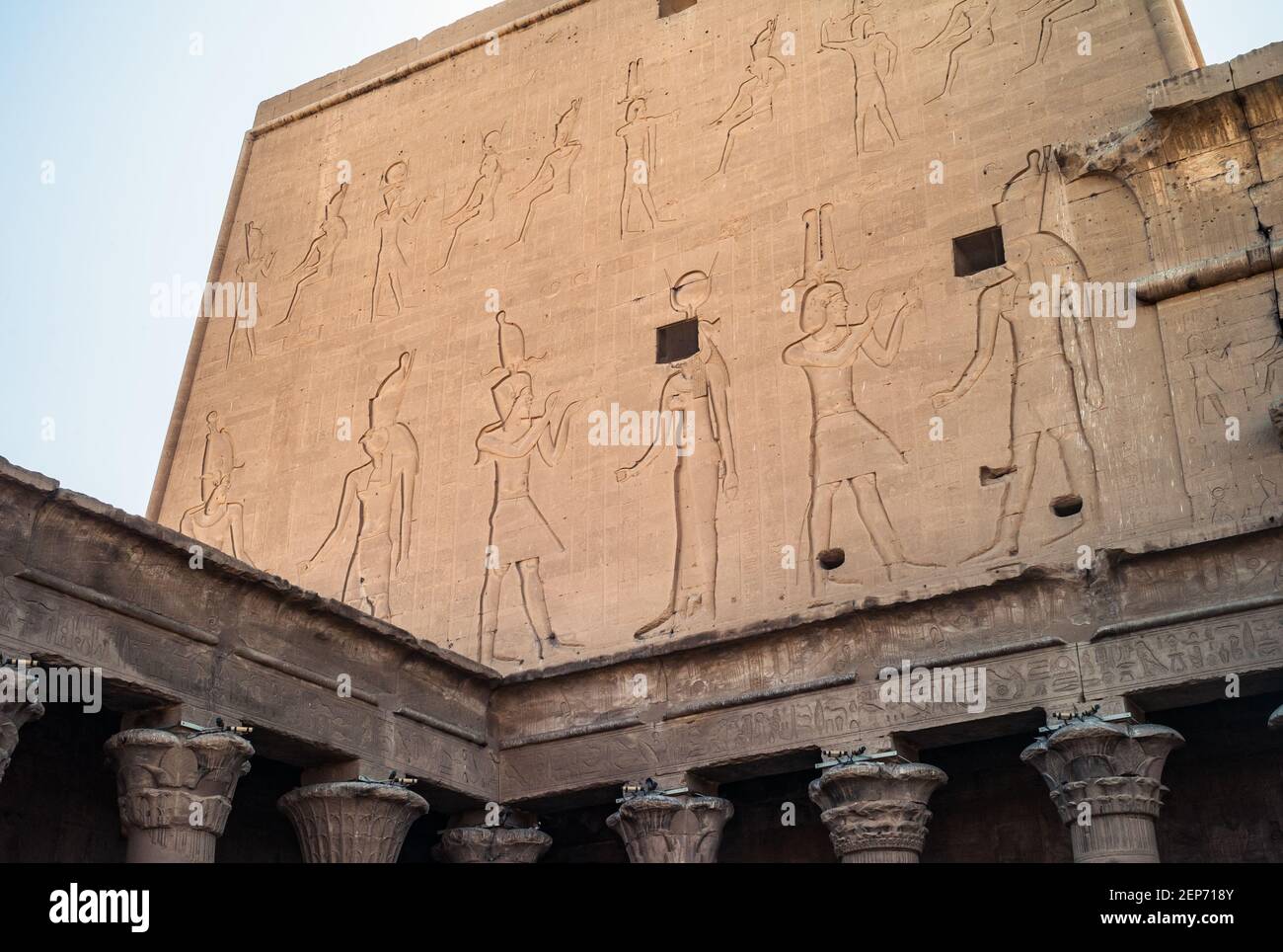 Temple Edfu - façade nord de l'aile est du Grand Pylon avec les reliefs du roi Ptolémée XII en interaction avec les dieux Horus et Hathoror. Banque D'Images