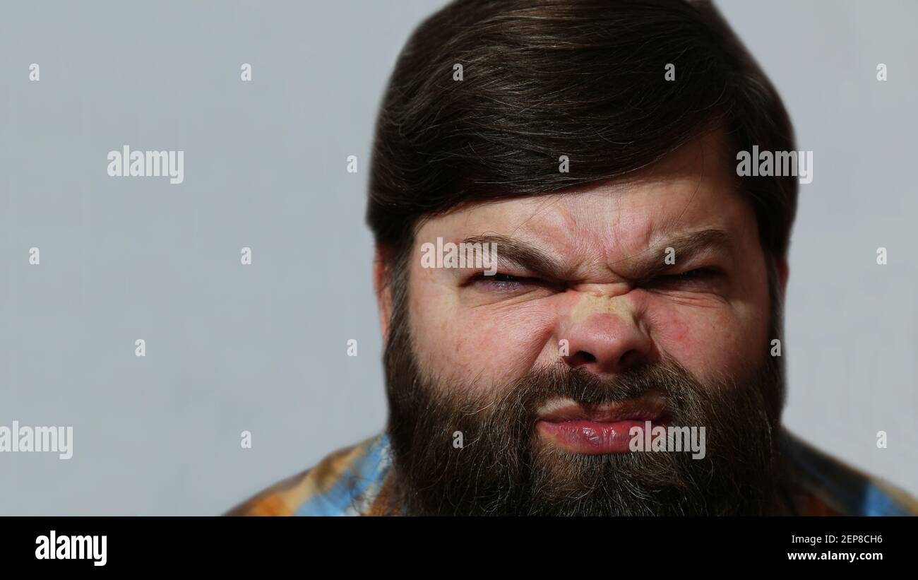 Portrait. Un barbu mécontent sur fond gris. Banque D'Images