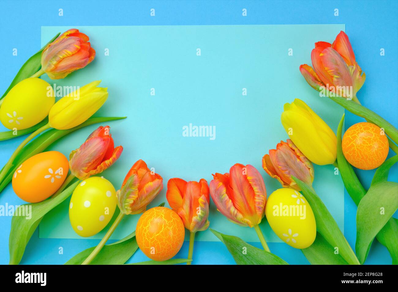 Vacances de Pâques.tulipes orange et jaune et oeufs décoratifs de pâques sur un fond bleu vif.espace de copie.symbole de vacances religieuses de printemps. Banque D'Images