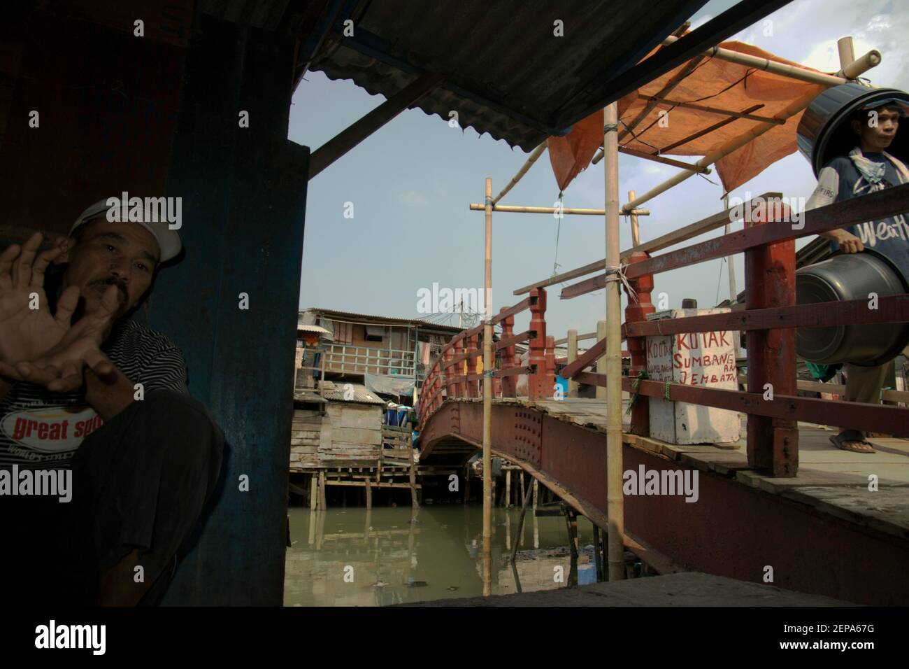 Portrait d'un homme comme il se détend à côté d'un pont sur un village populairement connu sous le nom de Luar Batang, sur l'estuaire de la rivière Ciliwung, près du port traditionnel de Sunda Kelapa dans la zone côtière de Jakarta, Indonésie (2008). Banque D'Images