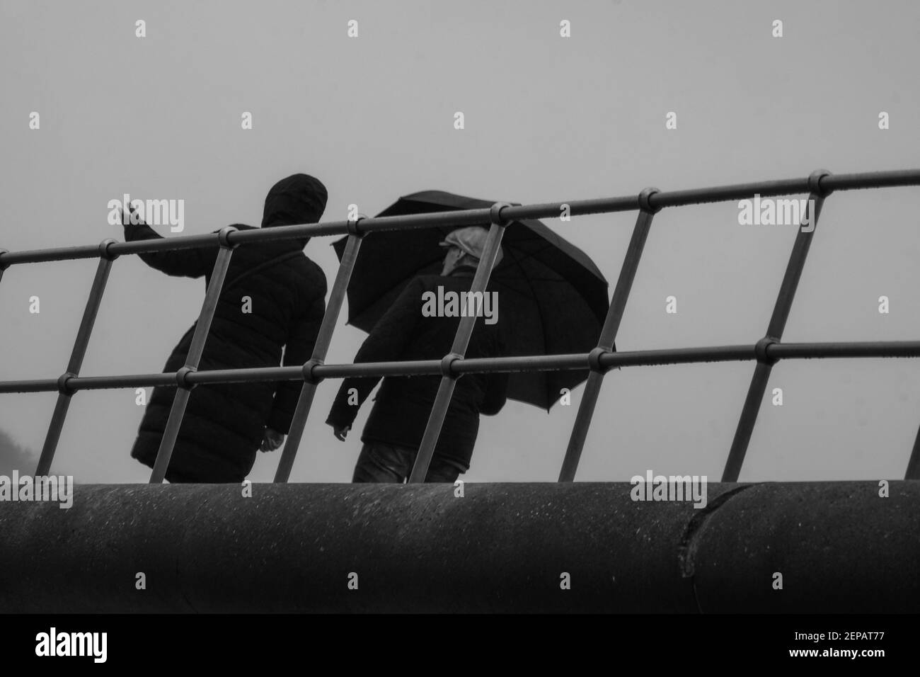 Couple de marche sentier côtier avec parapluie dans la pluie, Devon, Angleterre Banque D'Images