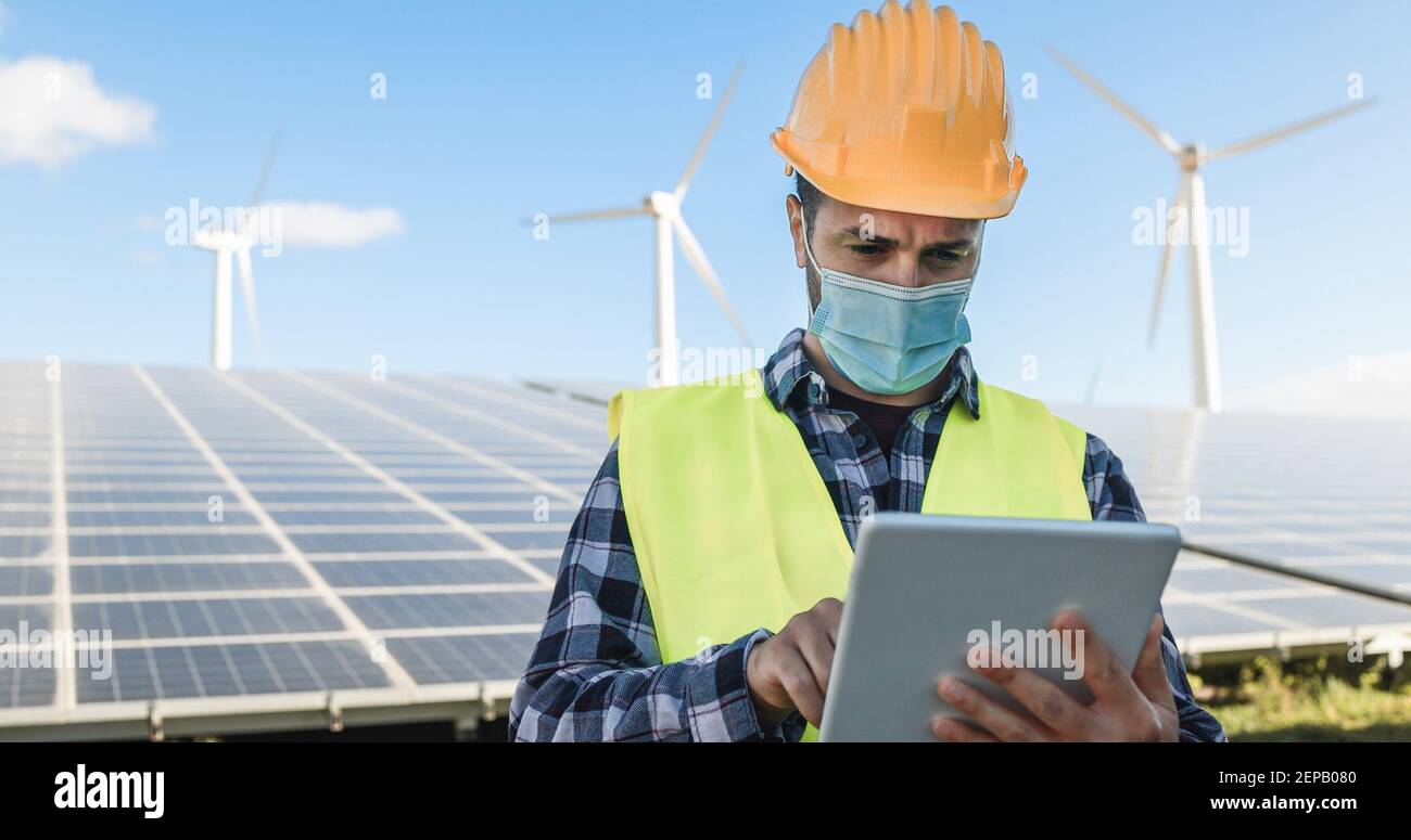 Homme utilisant une tablette numérique tout en portant un masque de sécurité à Exploitation d'énergie renouvelable pendant l'éclosion de coronavirus - attention douce face Banque D'Images