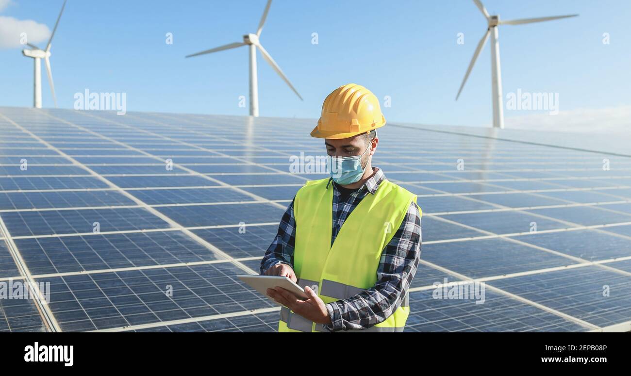 Homme utilisant une tablette numérique tout en portant un masque de sécurité à Exploitation d'énergie renouvelable pendant l'éclosion de coronavirus - attention douce face Banque D'Images