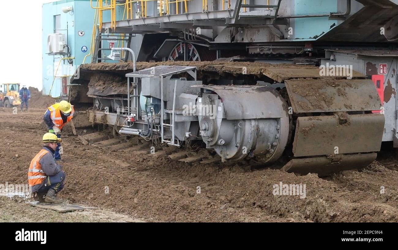 27 février 2021, GDR, Neukieritzsch: Des techniciens inspectent les maillons d'une pelle hydraulique à roue de 345 tonnes qui vient de traverser la Bundesstraße 176 entre Groitzsch et Neukieritzsch (district de Leipzig). La pelle hydraulique de 12.5 mètres de haut, de 43 mètres de long et de 12 mètres de large sera utilisée dans le domaine minier de Peres, a annoncé l'entreprise, le groupe énergétique Mibrag. Photo: Sebastian Willnow/dpa-Zentralbild/dpa Banque D'Images